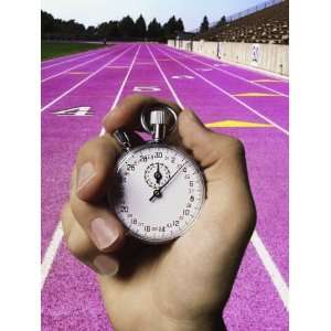  Persons Hand Holding a Stop Watch in Front of a Running Track 