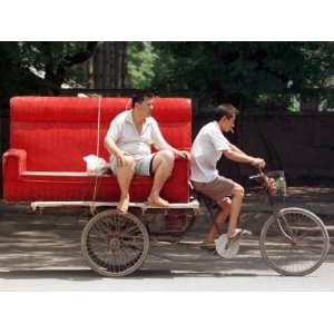  A Chinese Man Rides on a Sofa as Another Pedals a Delivery 